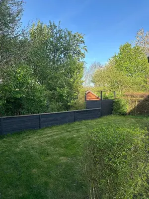 a fence in a yard with a field of grass at Sjarmerende og hyggelig lite hjem in Holstebro
