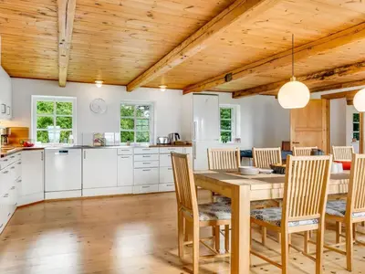 a kitchen and dining room with a wooden table and chairs at Holiday Home Åsta - 400m to the fjord by Interhome in Roslev