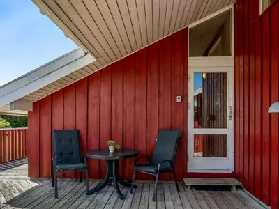 a patio with two chairs and a table on a red wall at Holiday Home Hans - 1-2km from the sea by Interhome in Løkken