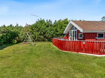 a red house with a playground in a yard at Holiday Home Hans - 1-2km from the sea by Interhome in Løkken