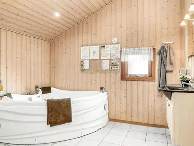 a white tub in a wooden bathroom with a sink at Holiday Home Hans - 1-2km from the sea by Interhome in Løkken