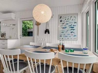 a dining room with a wooden table and white chairs at Holiday Home Blia - 120m to the fjord by Interhome in Løgstør