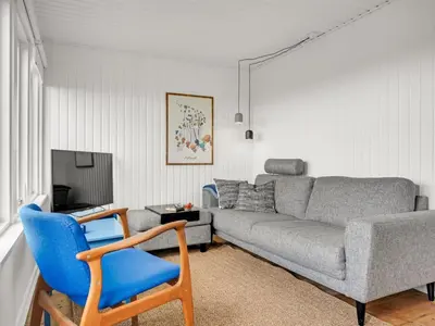 a living room with a couch and a blue chair at Holiday Home Blia - 120m to the fjord by Interhome in Løgstør