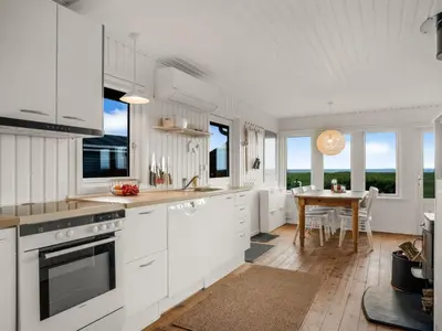 a kitchen with white cabinets and a wooden table at Holiday Home Blia - 120m to the fjord by Interhome in Løgstør