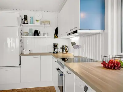 a kitchen with white cabinets and a wooden counter top at Holiday Home Blia - 120m to the fjord by Interhome in Løgstør