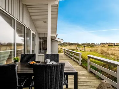 a wooden deck with a table and chairs on a house at Holiday Home Fridgerd - 300m from the sea by Interhome in Løkken
