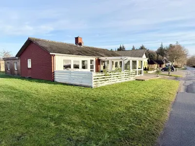 a red and white house on a grass field at Amtoft Vig Kitespot in Vesløs