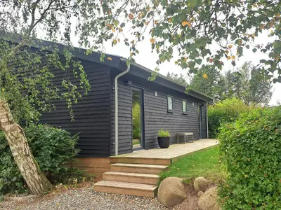 a black house with a wooden porch and a deck at Motel Glyngøre in Roslev