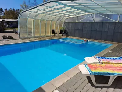 a swimming pool with a greenhouse and a swimming pool at Motel Glyngøre in Roslev