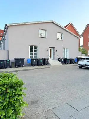 a white building with trash cans in a parking lot at Cozy Pearl in Viborg Centre in Viborg