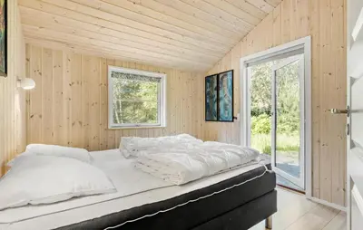 a bedroom with a large bed in a room with wooden walls at 4 Bedroom Stunning Home In Fjerritslev in Fjerritslev