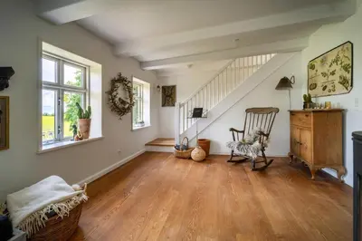 an empty living room with a chair and stairs at Country House With Fjord Views At Harre Vig in Roslev
