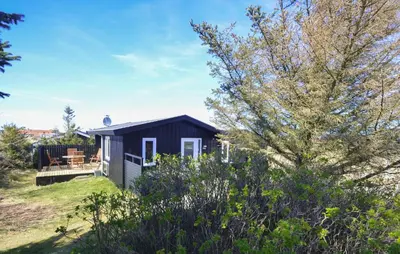 a small black shed with a deck in the grass at 2 Bedroom Pet Friendly Home In Thisted in Thisted