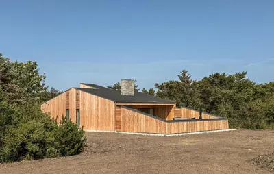 a wooden house with a black roof on a field at Cozy Home In Vestervig With Sauna in Vestervig
