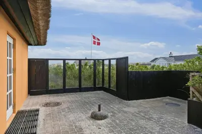 a balcony with a flag on top of a house at Thatched Holiday Home By The North Sea In Blokhus in Blokhus