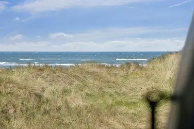 a view of the ocean from a field of grass at Thatched Holiday Home By The North Sea In Blokhus in Blokhus