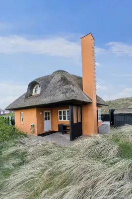 a house with a thatched roof on top of a field at Thatched Holiday Home By The North Sea In Blokhus in Blokhus
