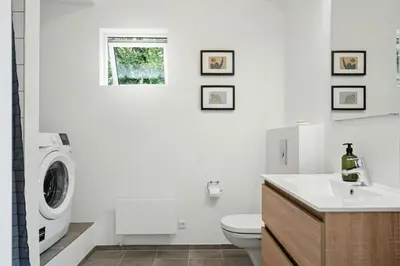 a white bathroom with a washing machine in it at Architect-Designed Wooden House At Ertebølle in Farsø