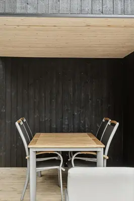 a wooden table and two chairs in front of a wall at Architect-Designed Wooden House At Ertebølle in Farsø