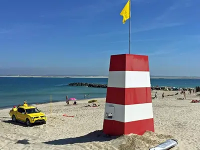 a yellow car parked next to a red and white lighthouse on a beach at 4 star holiday home in Thyborøn in Thyborøn