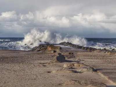 a wave crashing on a beach with rocks at 4 star holiday home in Thyborøn in Thyborøn