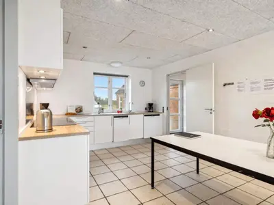 a kitchen with white cabinets and a table with a vase of flowers at 4 star holiday home in Harboøre in Harboør