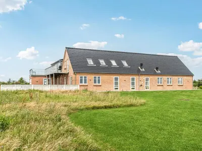 a brick house with a black roof on a grass field at 4 star holiday home in Harboøre in Harboør