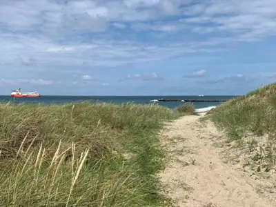 a dirt road leading to the beach with a ship in the ocean at 4 star holiday home in Thyborøn in Thyborøn