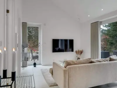 a living room with a couch and a tv on a wall at 4 star holiday home in Blokhus in Blokhus