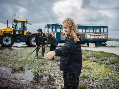 a woman is standing in a puddle with a bus at 4 star holiday home in Thyborøn in Thyborøn