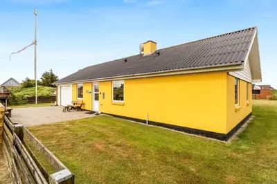 a yellow house with a black roof on a yard at Lovely Holiday Home With Fenced Plot, 300 Meters From The North Sea In Thy in Lild Strand