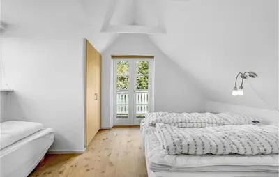 a white bedroom with two beds and a window at Holiday Home Spøttrup - 04 in Spottrup