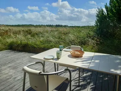 a picnic table with two chairs and a basket on it at Holiday Home Overlooking Protected Dune Heath in Frøstrup