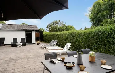 a patio with a table and chairs and an umbrella at Stunning Home In Blokhus With Wifi in Blokhus