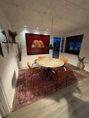 a dining room with a table and chairs on a rug at Villa Centrum in Holstebro