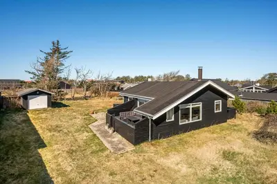 a house with a black roof on a yard at Pirupshvarrevej 5A in Blokhus