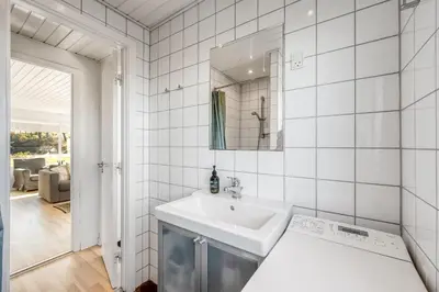 a white bathroom with a sink and a mirror at Pirupshvarrevej 5A in Blokhus