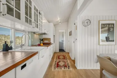 a kitchen with white cabinets and a clock on the wall at Forårsvangen 2 in Saltum
