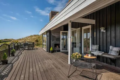 a wooden deck with a table and chairs on a house at Forårsvangen 2 in Saltum