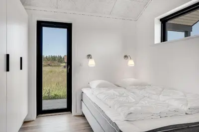 a white bedroom with a large bed and a window at Laustvej 3 in Saltum