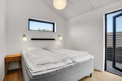 a white bedroom with a bed and a window at Laustvej 3 in Saltum