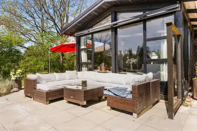 a patio with a white couch and wicker chairs at Granlien 3, A Holiday Home With Soul And Charm! in Blokhus