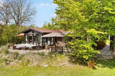 a house with a table and chairs in a yard at Granlien 3, A Holiday Home With Soul And Charm! in Blokhus
