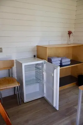 a small refrigerator in a room with a shelf at Aalborg Hytteø in Aalborg