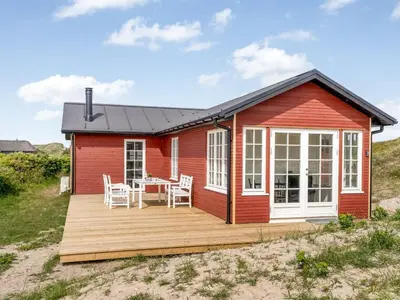 a red house with a table and chairs on a deck at Holiday Home Thine - 250m from the sea by Interhome in Harboør
