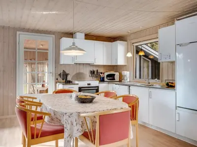 a kitchen with a table with chairs and a white refrigerator at Holiday Home Iris - 200m to the fjord by Interhome in Thyholm