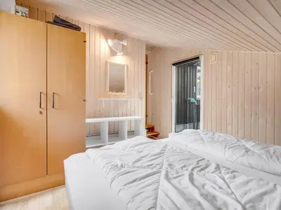 a bedroom with a white bed and a cabinet at Holiday Home Iris - 200m to the fjord by Interhome in Thyholm