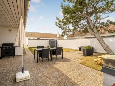 a backyard with a table and chairs and a grill at Holiday Home Aike - 1km from the sea by Interhome in Pandrup