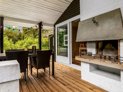 a patio with a fireplace and a table and chairs at Holiday Home Ginette - 400m to the fjord by Interhome in Åbybro