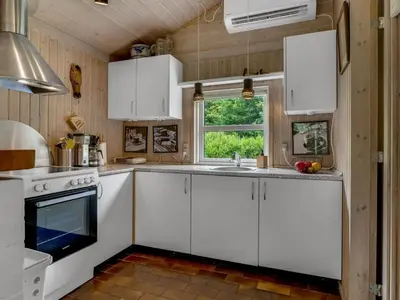a kitchen with white cabinets and a sink and a window at Holiday Home Ginette - 400m to the fjord by Interhome in Åbybro